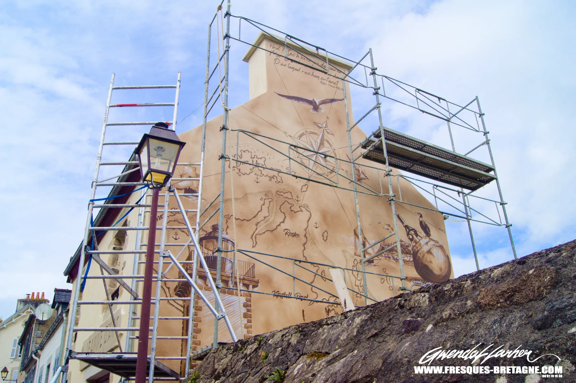 Chantier sur échafaudage pendant la réalisation de la fresque sur le pignon d'une maison à Locquénolé